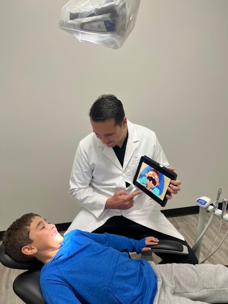 Dr. Jose Hernandez showing a young patient an educational video at Chemi Dental